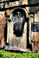 [picture: Weathered gravestone set into old stone wall]