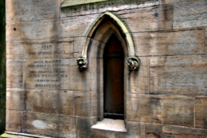 [picture: Arched stone window with carvings and inscription]