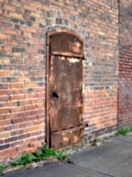 [picture: Rusty metal door in a brick wall]